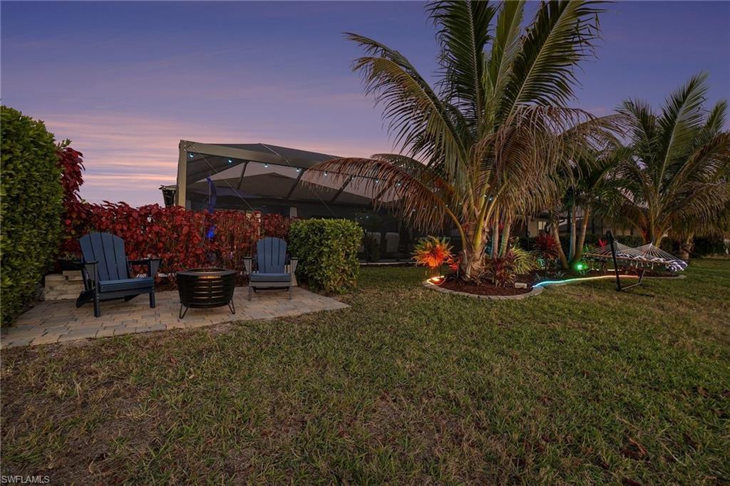 Yard at dusk featuring glass enclosure, a yard, and a patio area