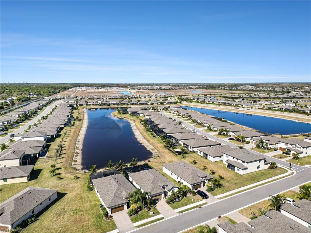 Aerial view of property and surrounding area featuring nearby suburban area and a large body of water