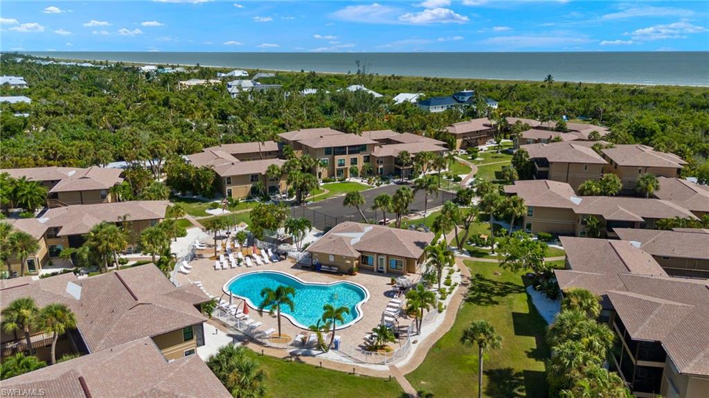 Aerial view of residential area featuring a nearby body of water and a pool