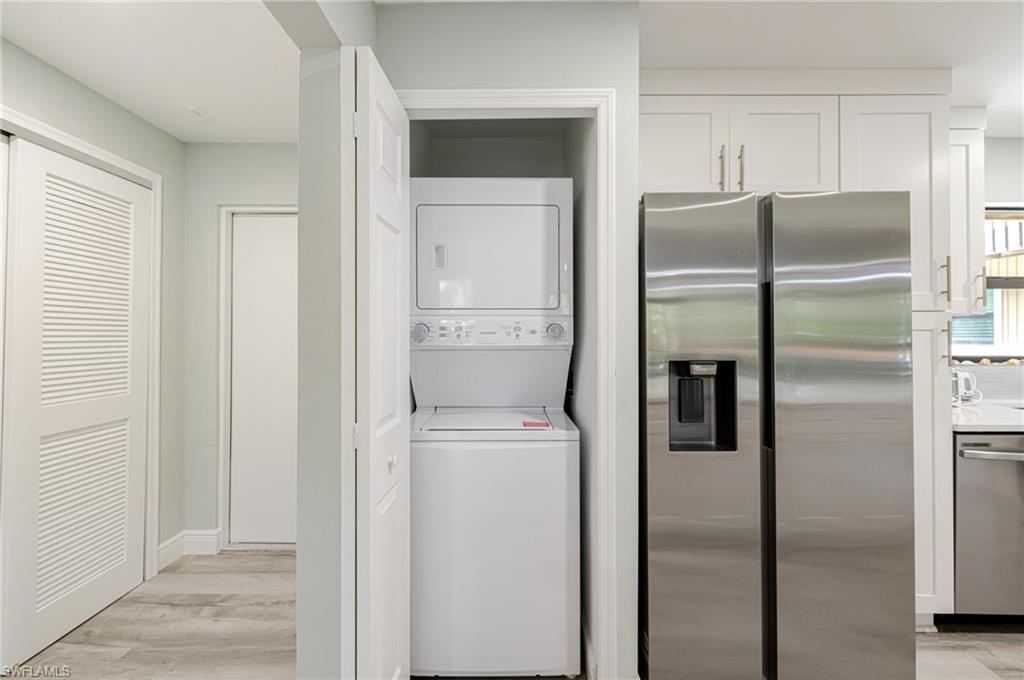 Laundry area featuring stacked washer / dryer and light wood-type flooring