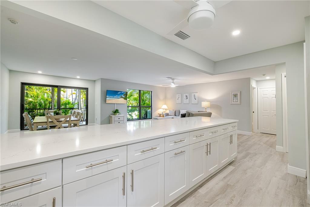 Kitchen featuring white cabinetry, open floor plan, light wood-type flooring, recessed lighting, and light stone countertops