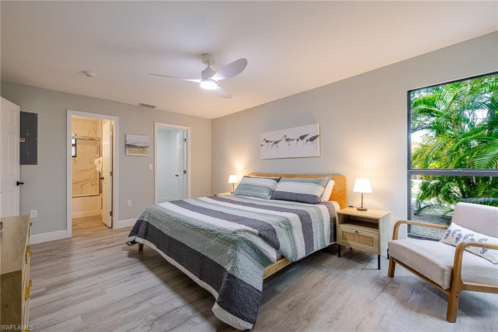 Primary Bedroom with light wood-type flooring, electric panel, a ceiling fan, and ensuite bath