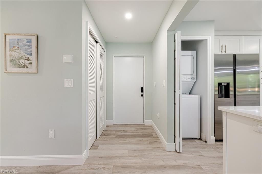 Laundry area featuring stacked washer / dryer and light wood-type flooring