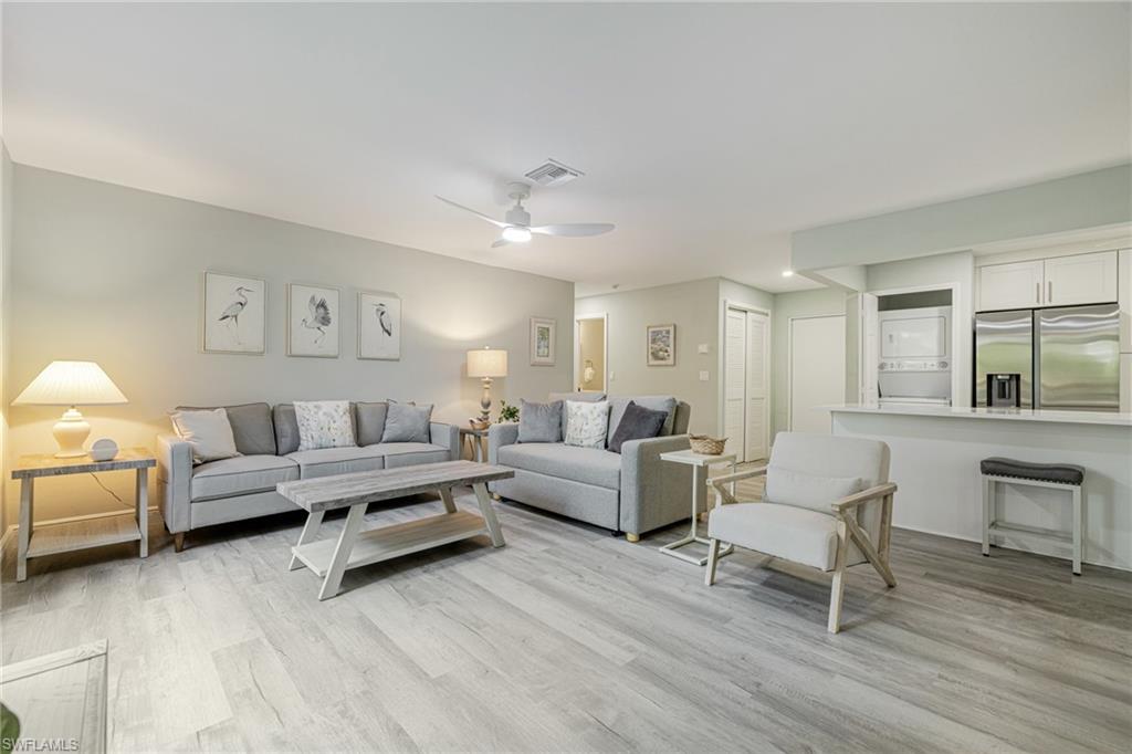 Great room featuring light wood-style flooring, a ceiling fan, and stacked washer / drying machine