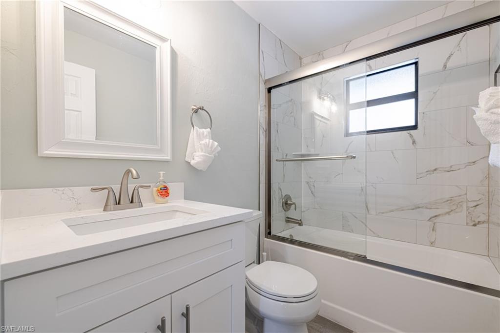 Primary bath featuring shower / bath combination with glass door and vanity