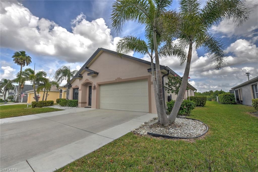 Ranch-style home featuring stucco siding, a front lawn, driveway, and a garage