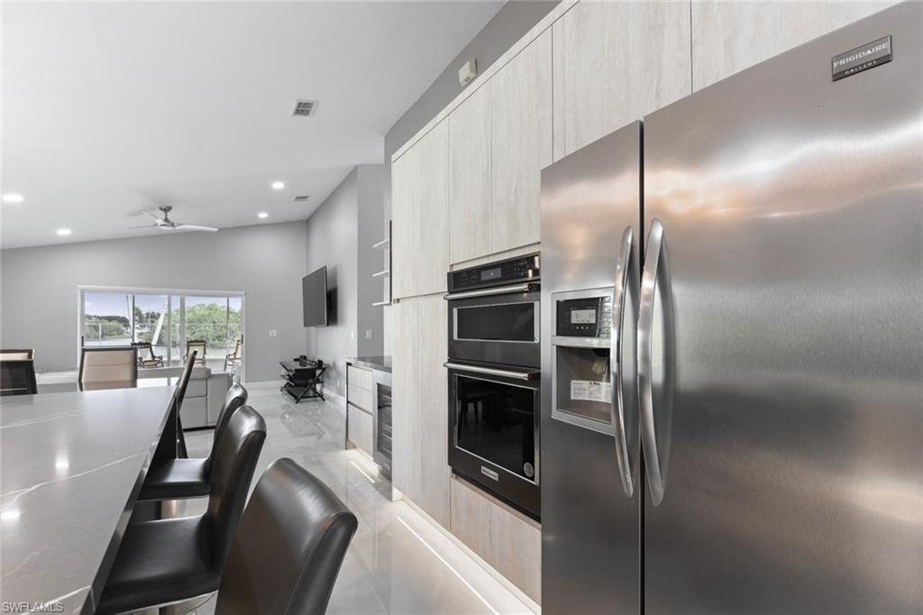 Kitchen with stainless steel refrigerator with ice dispenser, modern cabinets, ceiling fan, lofted ceiling, and recessed lighting