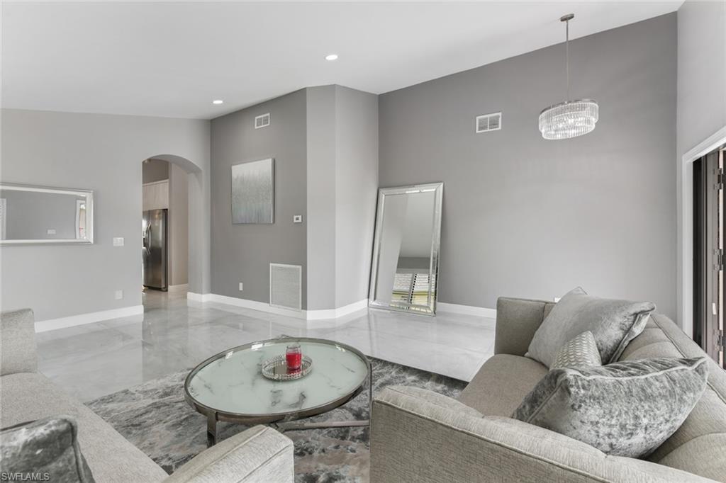 Living room featuring arched walkways, a high ceiling, and recessed lighting