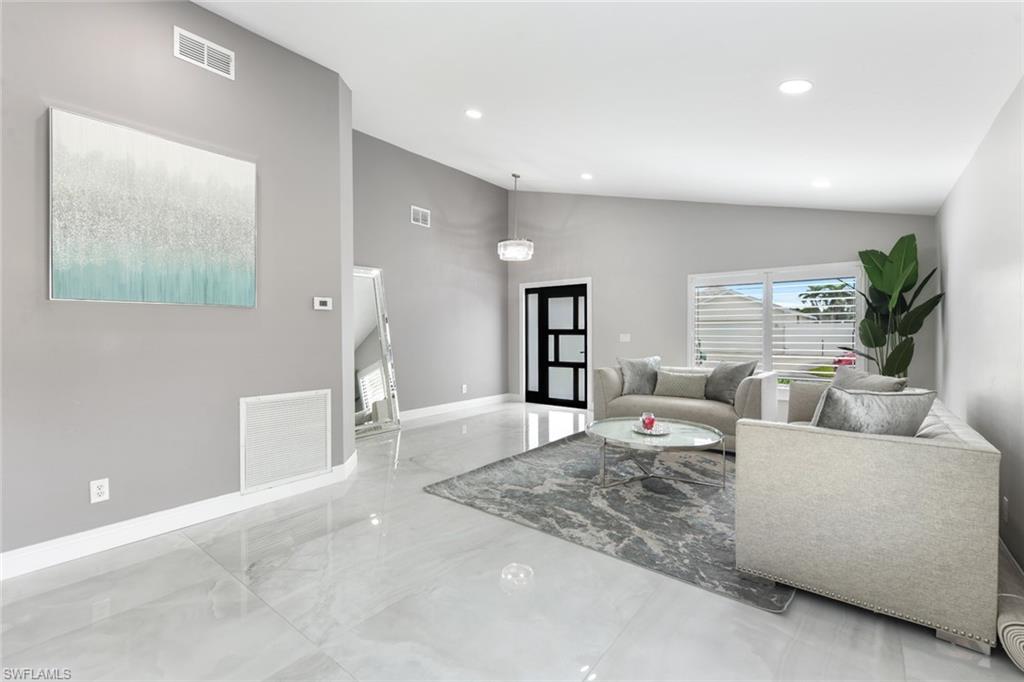 Living room with lofted ceiling, recessed lighting, and marble tiled flooring