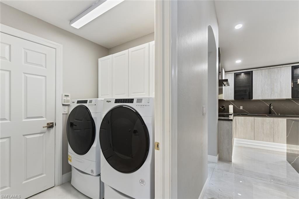 Laundry area with washing machine and clothes dryer, cabinet space, arched walkways, and recessed lighting