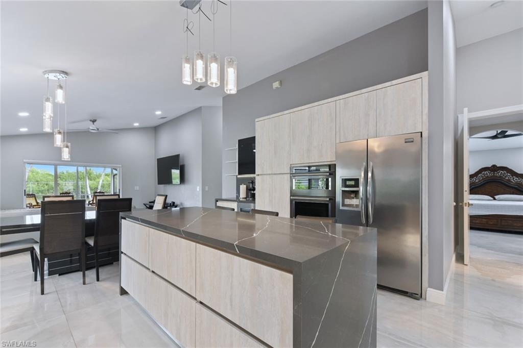 Kitchen with light wood finish cabinets, ceiling fan, decorative light fixtures, and stainless steel appliances