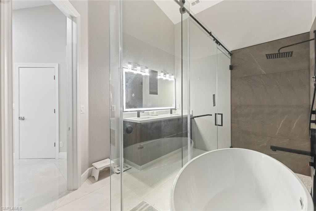 Full bathroom with a shower stall, double vanity, and a freestanding tub