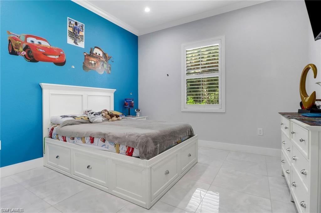 Bedroom with ornamental molding and light tile patterned floors