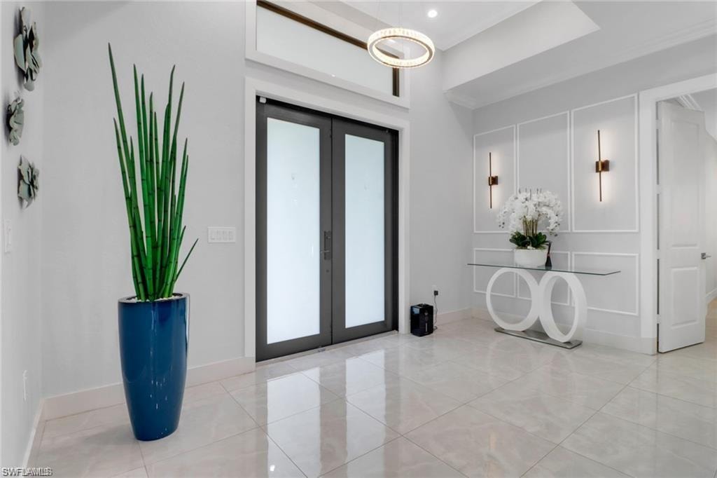 Foyer entrance with french doors, light tile patterned floors, and a decorative wall
