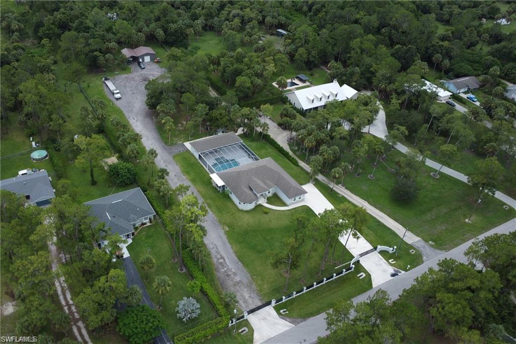 Aerial view of property and surrounding area with a forest and nearby suburban area