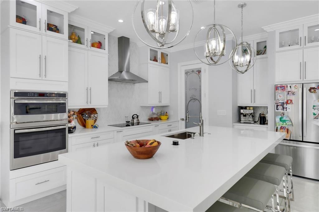 Kitchen with glass fronted cabinets, stainless steel appliances, white cabinets, and ornamental molding