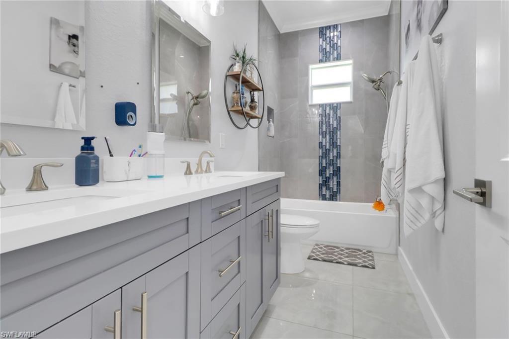 Bathroom featuring tub / shower combination, double vanity, and light tile patterned flooring