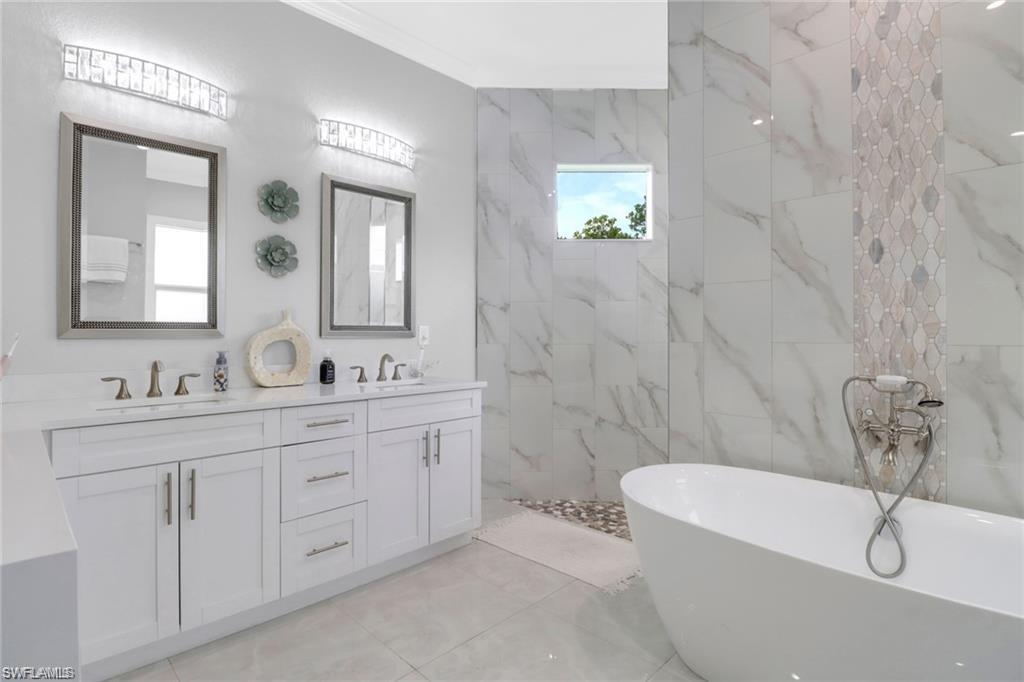 Full bath featuring a freestanding bath, double vanity, and a marble finish shower