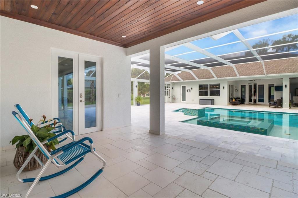Combined pool / hot tub with french doors, a patio area, glass enclosure, and a sunroom