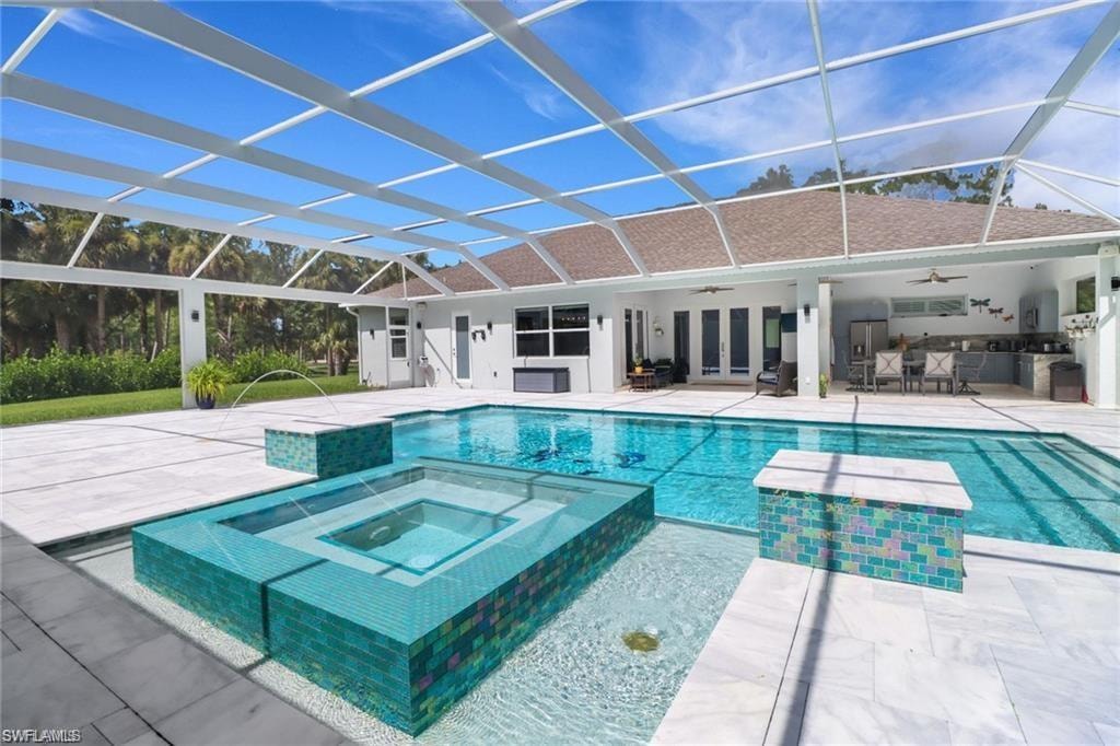 Relaxing pool / spa featuring a sunroom, a patio, and a lanai