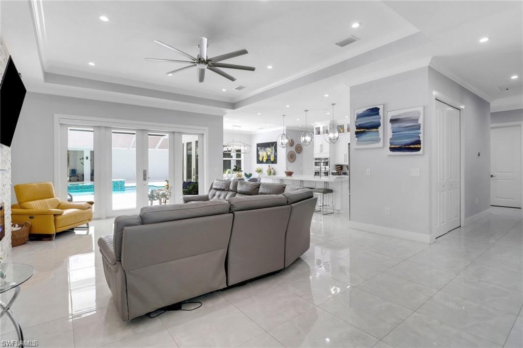 Living room with a tray ceiling, a ceiling fan, crown molding, and recessed lighting