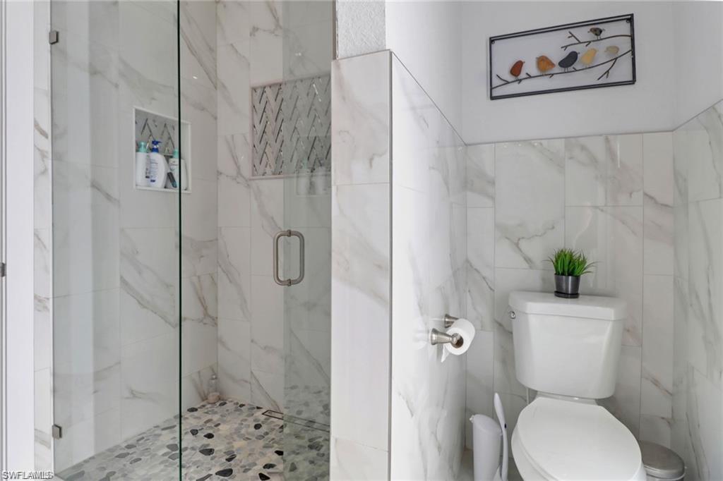 Full bathroom featuring a marble finish shower and tile walls