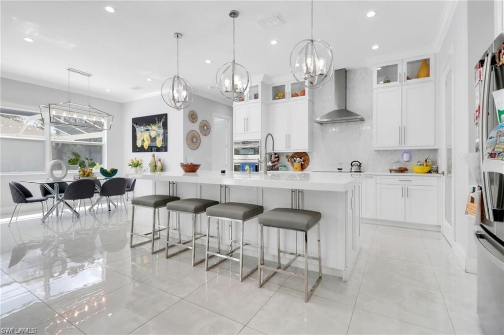 Kitchen featuring white cabinets, a breakfast bar, suspended lighting, glass insert cabinets, and stainless steel appliances