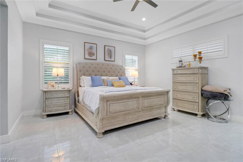 Bedroom featuring ceiling fan, ornamental molding, and a tray ceiling