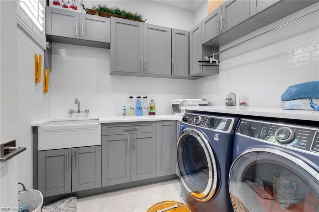 Laundry area featuring cabinet space, separate washer and dryer, and light tile patterned flooring