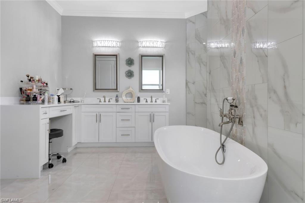 Bathroom with double vanity, a freestanding bath, and ornamental molding