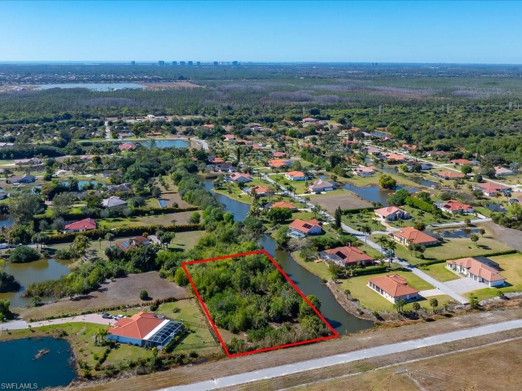 Aerial perspective of suburban area with a nearby body of water and property boundaries highlighted