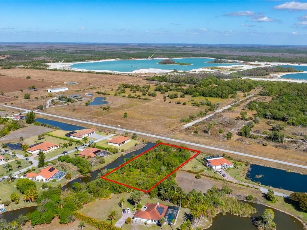 Aerial view of property and surrounding area featuring a nearby body of water and property parcel outlined