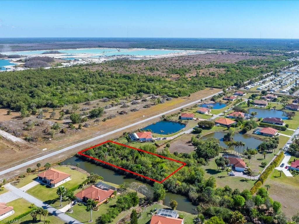 Aerial perspective of suburban area with property parcel outlined and a nearby body of water