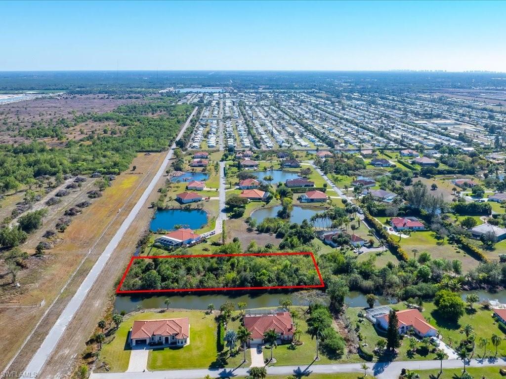 Aerial perspective of suburban area featuring property parcel outlined and a nearby body of water