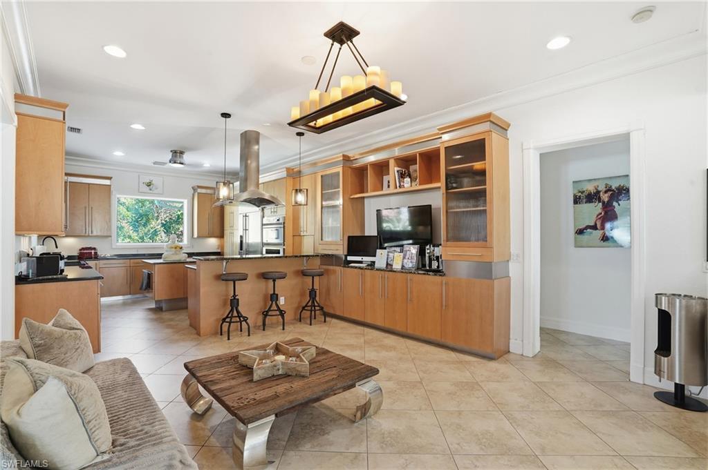 Living room with crown molding, light tile patterned floors, and a chandelier