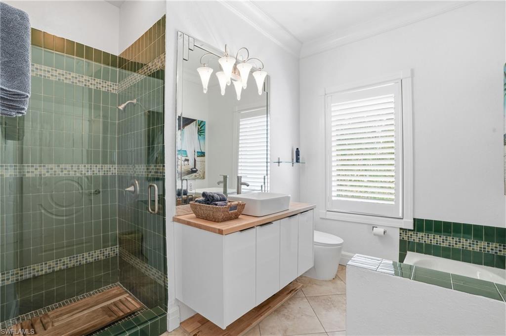 Bathroom with vanity, a stall shower, crown molding, light tile patterned flooring, and a chandelier