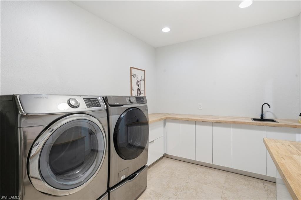 Laundry area featuring washer and clothes dryer, recessed lighting, and cabinet space