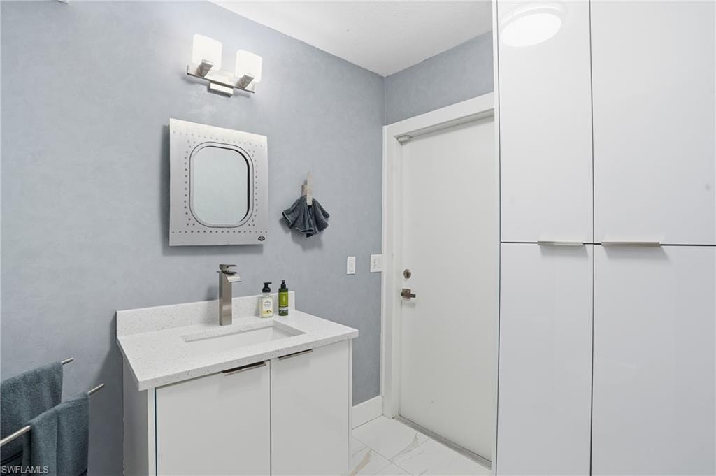 Half bathroom with vanity and light marble finish floors