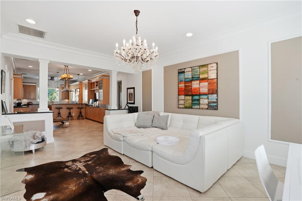 Living area featuring ornate columns, crown molding, suspended lighting, and light tile patterned flooring