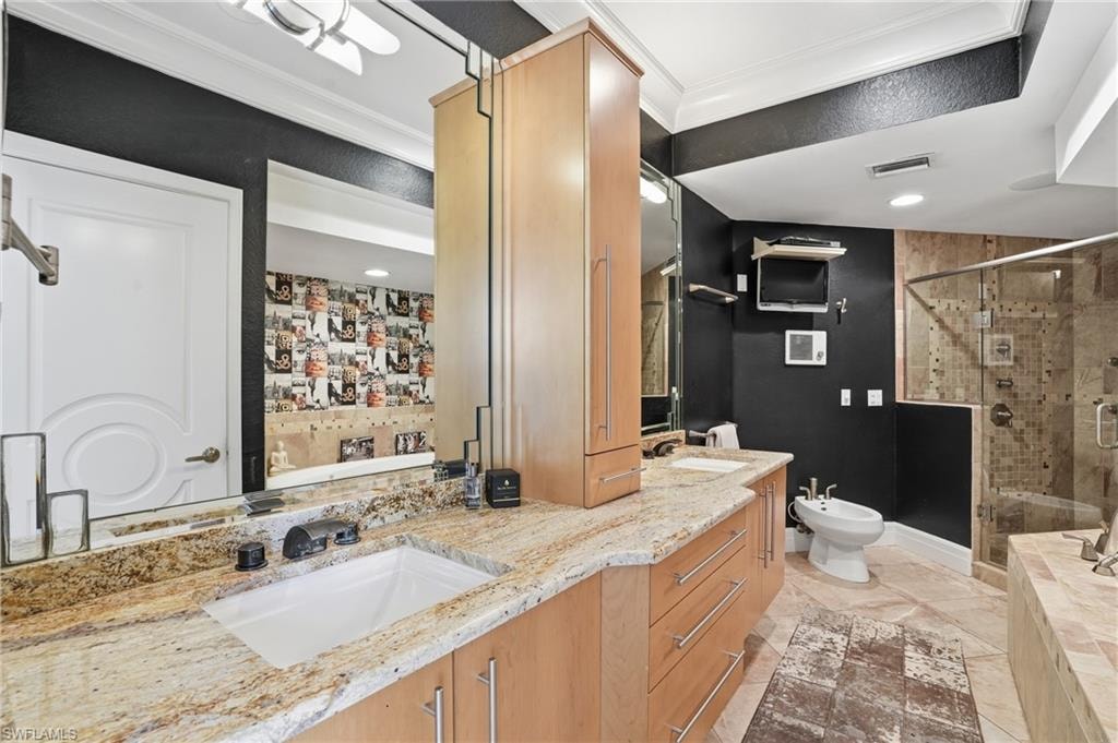 Full bathroom featuring double vanity, ornamental molding, a bidet, a stall shower, and a relaxing tiled tub
