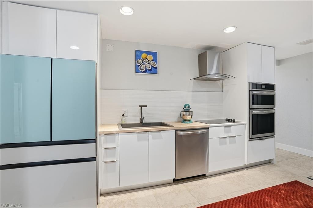 Kitchen featuring stainless steel appliances, decorative backsplash, modern cabinets, white cabinets, and light countertops