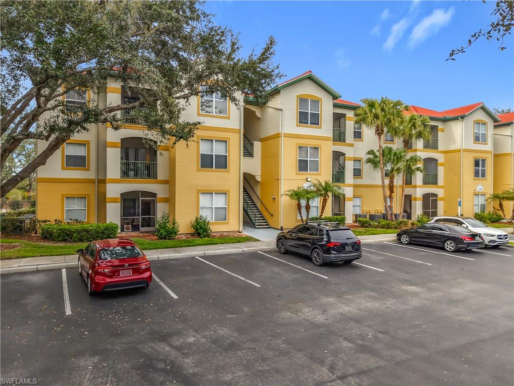 View of apartment building / complex with stairs and uncovered parking
