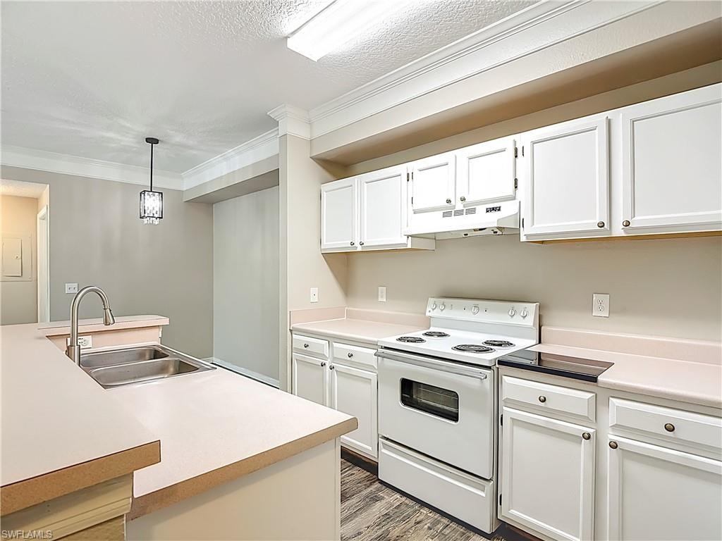 Kitchen featuring white electric range, light countertops, pendant lighting, white cabinets, and crown molding