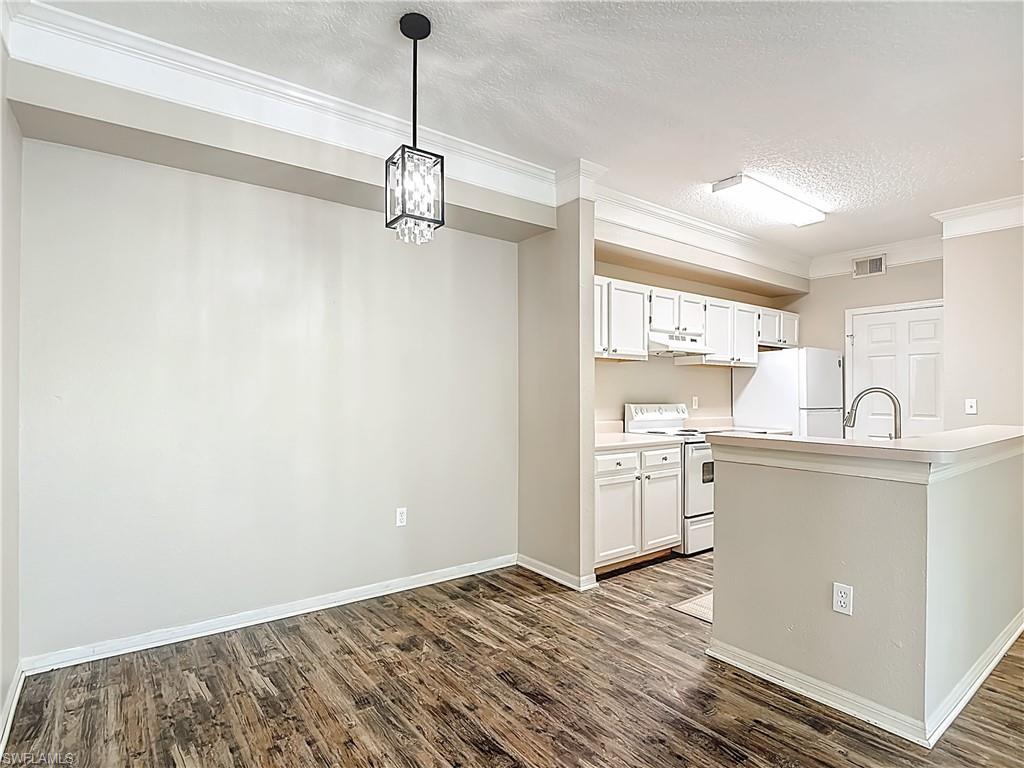 Kitchen featuring light countertops, white appliances, white cabinetry, a textured ceiling, and crown molding