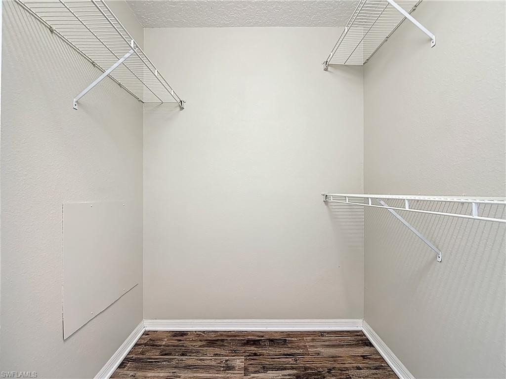 Walk in closet featuring dark wood-style floors
