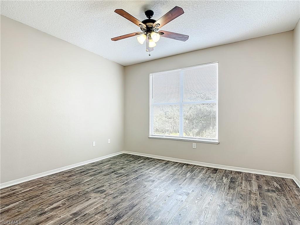Spare room with wood finished floors, a textured ceiling, and a ceiling fan