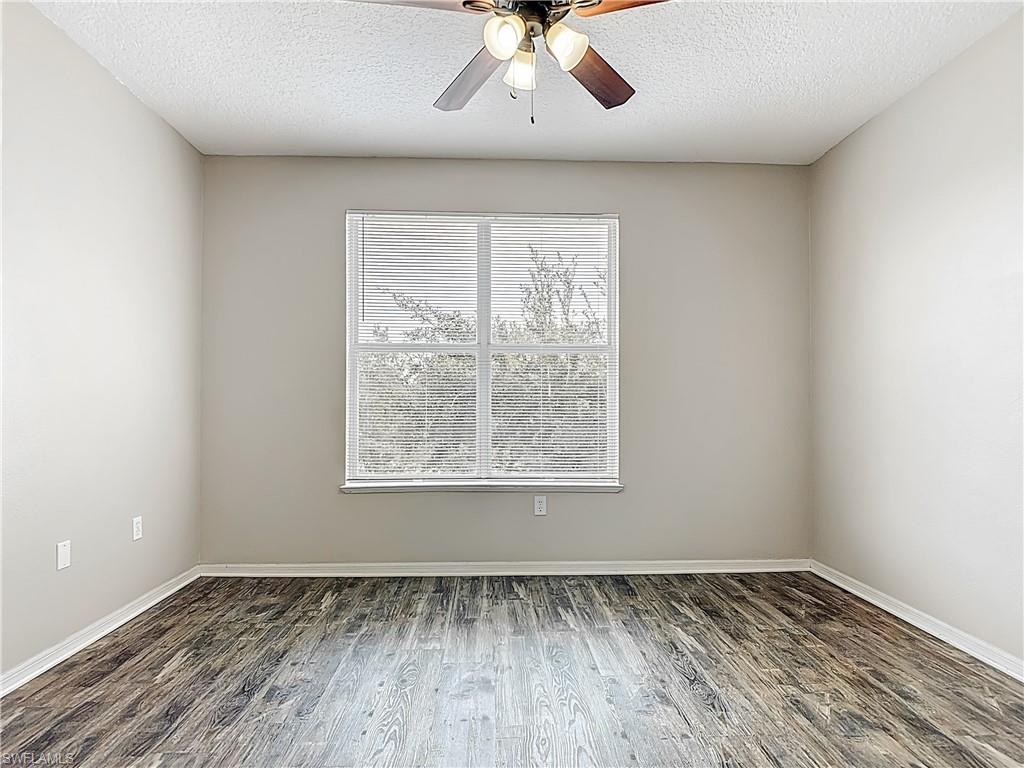Unfurnished room with ceiling fan, dark wood-style floors, and a textured ceiling