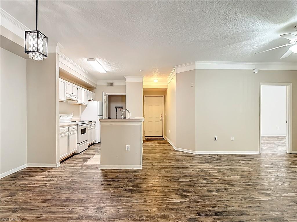 Kitchen with white cabinets, light countertops, white electric range, crown molding, and a textured ceiling