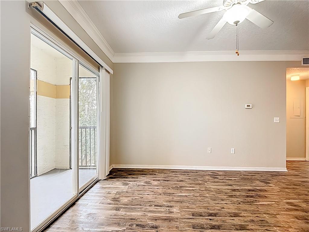 Unfurnished room featuring a ceiling fan, ornamental molding, wood finished floors, and a textured ceiling