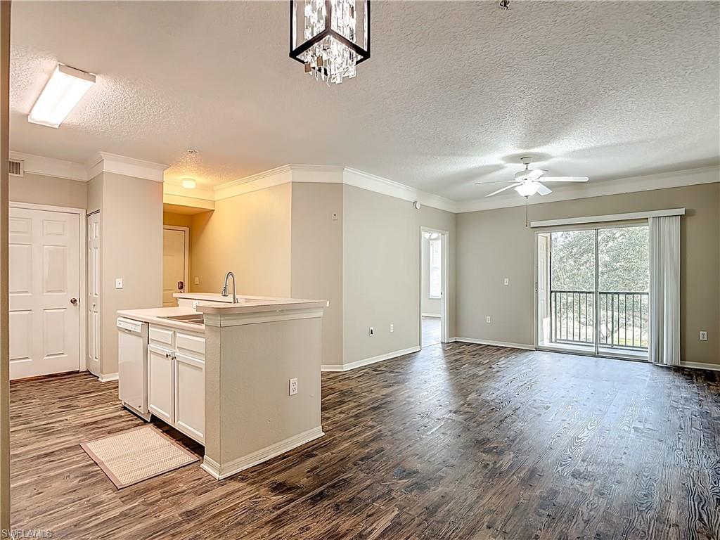 Kitchen with white cabinets, light countertops, crown molding, dark wood-style flooring, and a textured ceiling